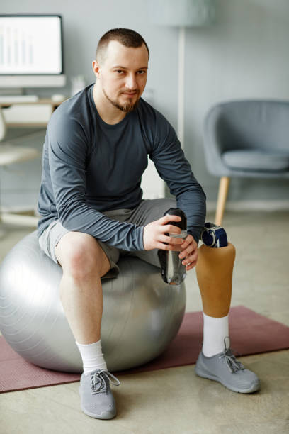 istock Man with prosthetic leg in home workout 1442830986