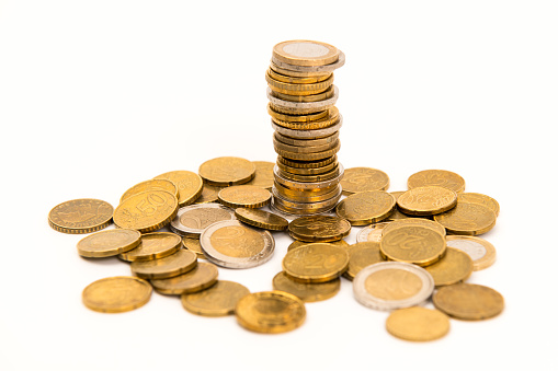A tower and a heap of Euro coins from 10 cent through 2 Euro on a white background.