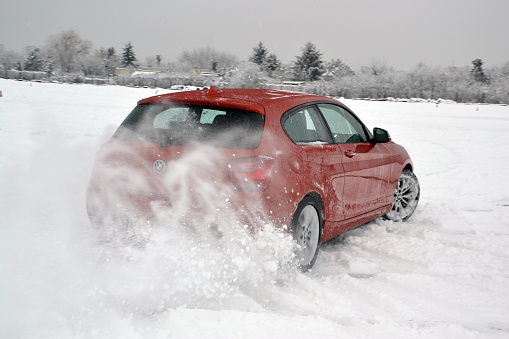 Warsaw, Poland – 9th February, 2013: BMW M135i driving in winter scenery. This model was one of the fastest compact cars on the market. Focus on the rear wheel.