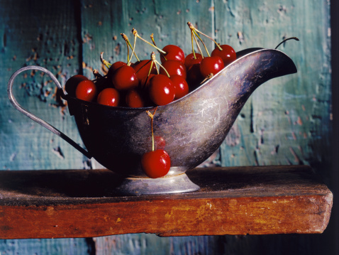 cherries in a silver gravy boat on a wooden shelf. More XXXL Still Life