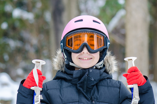 Headshot of teenage girl with ski helmet. goggle and holding ski poles during winter day