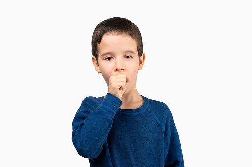 Young little boy kid wearing blue shirt standing over isolated background feeling unwell and coughing as symptom for cold or bronchitis. Health care concept.