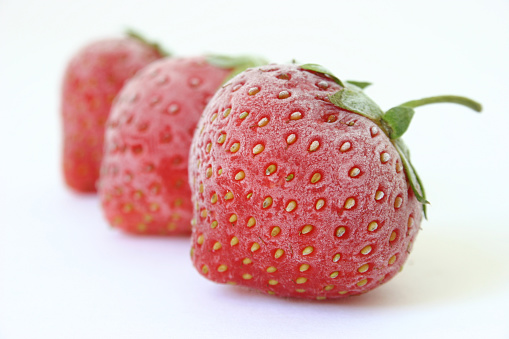 three frozen strawberries on white background