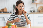 Healthy lifestyle. Happy caucasian woman holding nutritional supplement capsule or painkiller and glass of water, smiling friendly