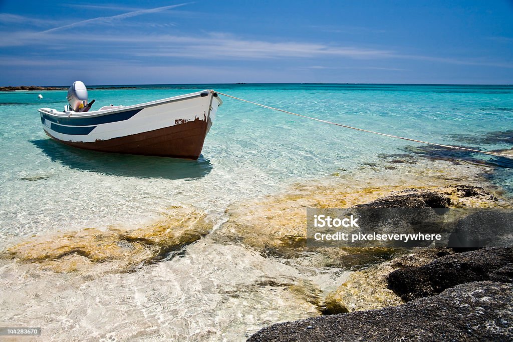 Single boat sitting off the coast Lonely boat in sunny waters at Elafonissi beach, Crete, Greece After Work Stock Photo