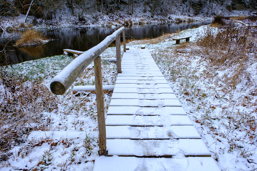 Landscapes, objects, concept of natural beauty. Old wooden small bridge. Skanaiskalns nature park. November is the first snow in Mazsalaca in Latvia