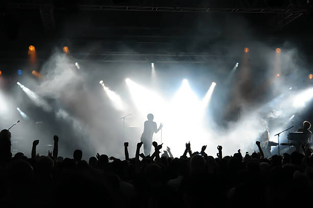 Man on stage with concert crowd below and bright spotlights stock photo