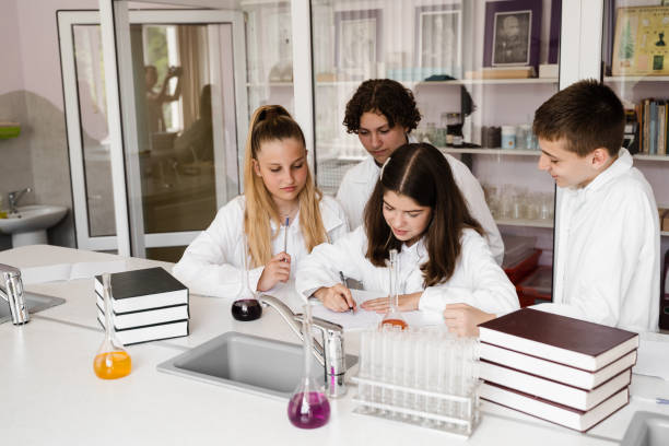 dyskusja z nauczycielem na lekcji chemii w laboratorium. grupa kolegów z klasy omawia eksperymenty chemiczne i prace domowe w szkole. koncepcja edukacji. - scholastic aptitude test zdjęcia i obrazy z banku zdjęć