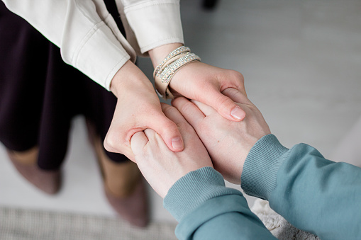A woman psychologist holds the hands of the patient and holds the hand and listens. Patient consultation. Metal health. Psychologist support.