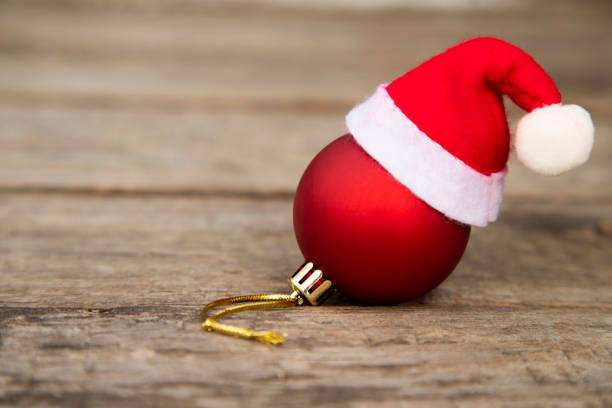 Christmas ball with Santa hat on wooden table