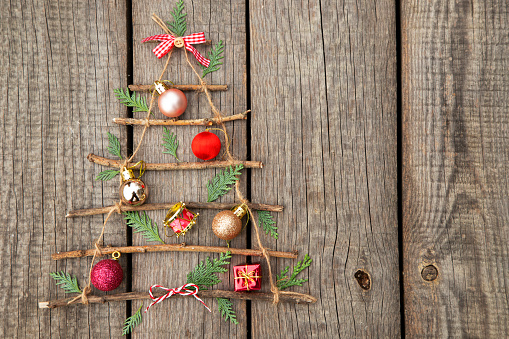 Creative Christmas tree made of wooden sticks and ornaments  on wooden background with copy space