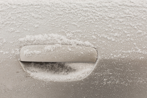 Car door knob close-up. Car under snow. Winter weather. Climate. Storm. Transportation