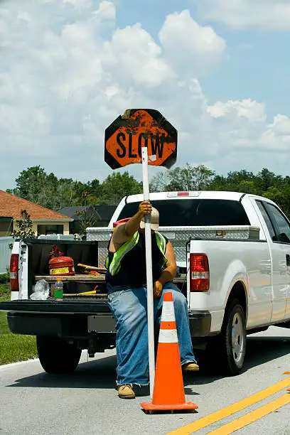 Bored looking man sitting on truck directing traffic to slow down with face occluded