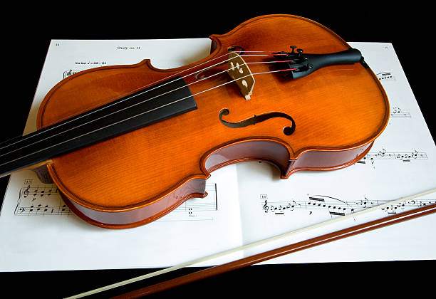 Violin and a Bow on Music Sheet This is a close-up of a violin and a bow on a music sheet.  chamber orchestra stock pictures, royalty-free photos & images