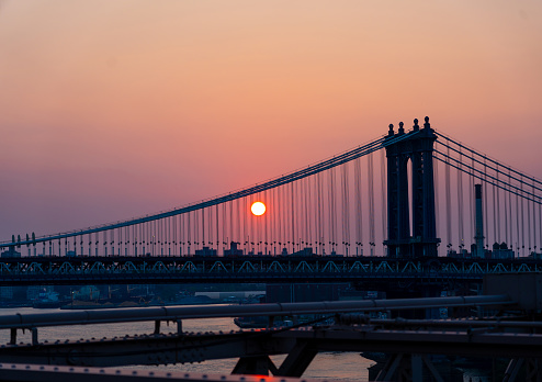 Manhattan bridge at dusk and setting sun disc.