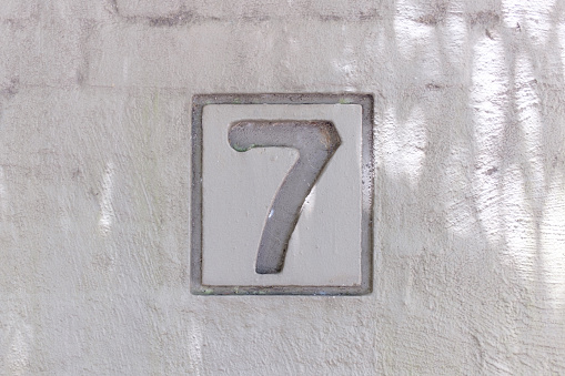 Close up of a street number “ 7 “ on a wall.