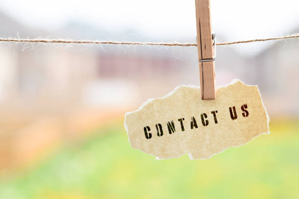 istock Contact Us phrase printed on torn paper hanging on a string with clothespin 1442856391