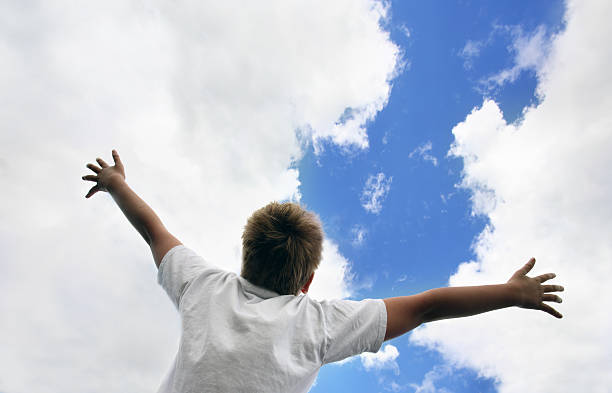 istock Young blonde boy with white blows throws hands at cloudy sky 144285876
