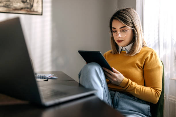 istock Concentrated young beautiful woman using digital tablet at her home 1442861109