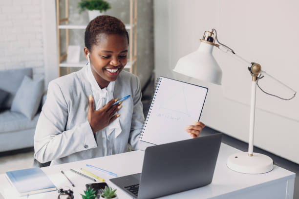 istock Black female tutor having video call with students, talking at laptop camera, sitting at table at home. Videoconference remote computer app virtual meeting. People lifestyle. Business meeting. Web meeting. 1442868637