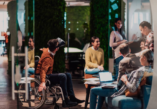 istock Business persons with a disability at work in modern open space coworking office on team meeting using virtual reality goggles. 1442871626