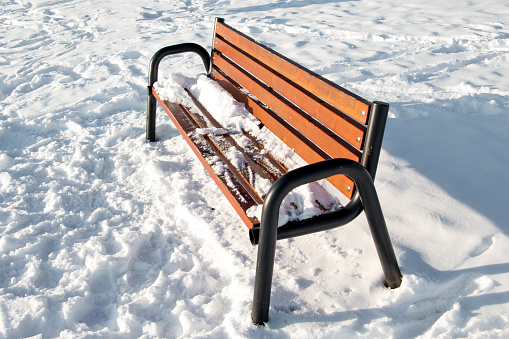 Wooden bench in the public park in snowed. Winter in outdoor.