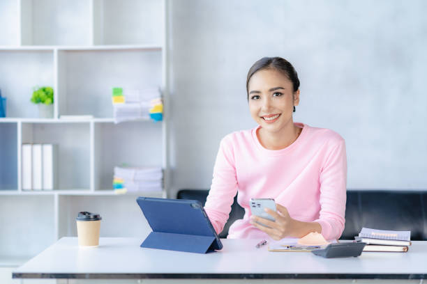 mulher asiática que trabalha on-line com tablet mulher jovem feliz que trabalha em casa - distance running audio - fotografias e filmes do acervo