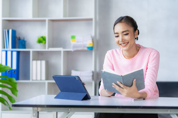 mulher asiática que trabalha on-line com tablet mulher jovem feliz que trabalha em casa - distance running audio - fotografias e filmes do acervo