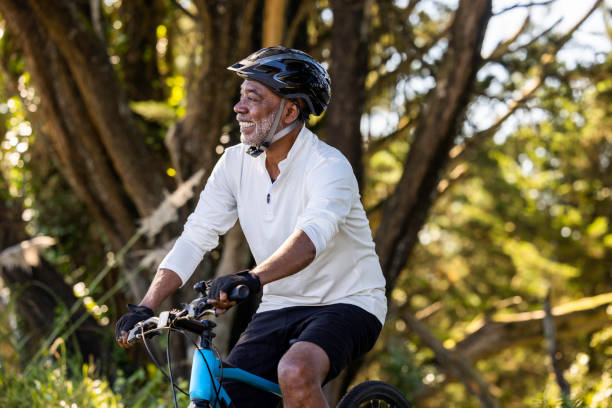 African American Man Cycling High quality stock photos of an African American man exercising and riding a bike outdoors in a wooded area on a trail and off. man 60s bicycle stock pictures, royalty-free photos & images