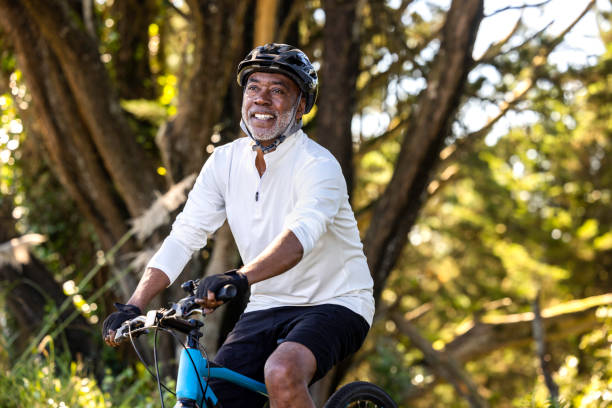African American Man Cycling High quality stock photos of an African American man exercising and riding a bike outdoors in a wooded area on a trail and off. man 60s bicycle stock pictures, royalty-free photos & images