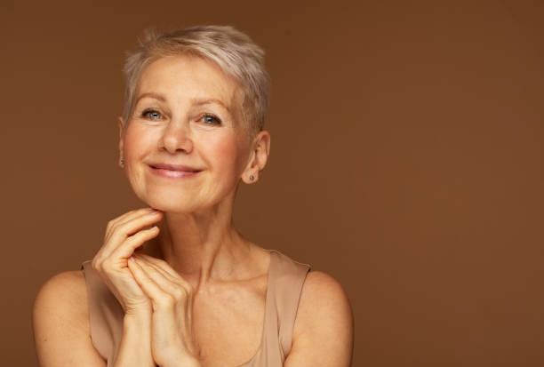 Beauty portrait of mature woman smiling with hand on face. stock photo