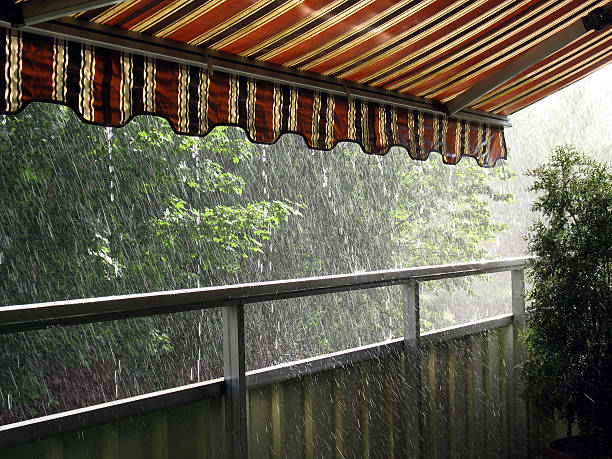 Heavy rain falling on the patio roof and on the trees Heavy rain in the summer time under an awning Sunblind stock pictures, royalty-free photos & images