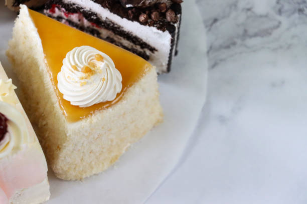 immagine ravvicinata di fette di varietà gateaux su cerchio di carta pergamena oleata, torta al caramello salato, torta angel food, gateau della foresta nera, sfondo effetto marmo, vista elevata, messa a fuoco in primo piano, spazio di copia - chocolate part of portion chocolate shaving foto e immagini stock