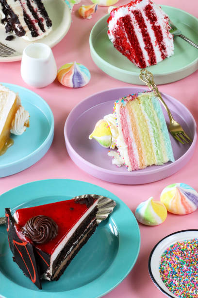 istock Close-up image of gateaux slice varieties on multicoloured plates, chocolate cherry cake, Black Forest gateau, red velvet, rainbow cake, coffee marbled chocolate gateau, pink background, focus on foreground 1442893207