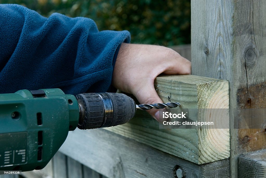 DIY craftsman is drilling A DIY craftsman is rebuiding a tree house in the garden, drillling in wood Blue Stock Photo