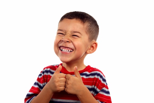 A 6 year old boy giving thumbs up and making a silly face, isolated on white background with copy space