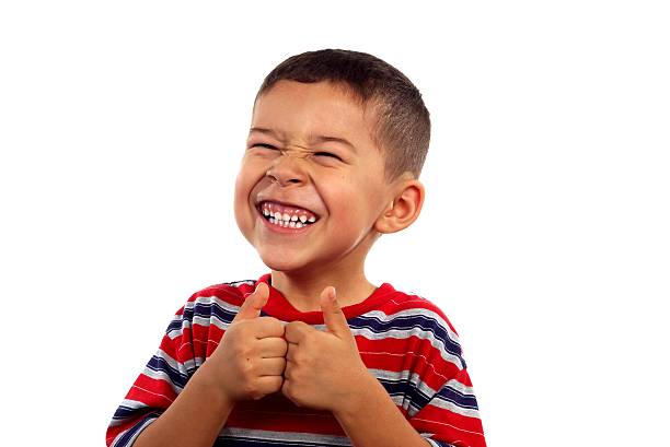 kid 6 years old silly face thumbs up A 6 year old boy giving thumbs up and making a silly face, isolated on white background with copy space ian stock pictures, royalty-free photos & images