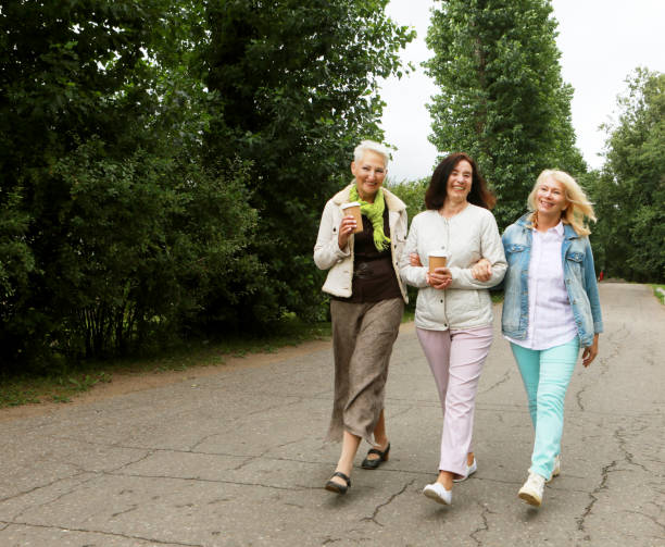 istock Three beautiful elderly women are walking in the park, having fun talking and drinking coffee. 1442895342