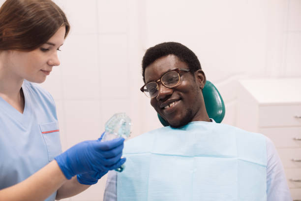 istock Young female dentist showing a black man an artificial jaw 1442895359