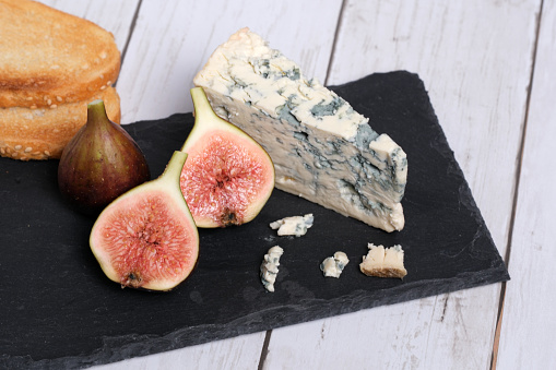 Sliced figs and blue cheese on black slate and isolated on wooden background.
