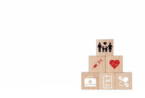 Square wooden blocks convey family stories and health. There are red cross icons with syringe, medicine, pill bag on a white background, leave a blank space to insert text for promotional materials, pictures taken and edited in Photoshop by Thai people for everyone