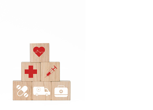 The square wooden blocks tell the story of health. There are red cross icons with syringe, medicine, pill bag and ambulance on a white background, leave a blank space to insert text for promotional materials, pictures taken and edited in Photoshop by Thai people for everyone