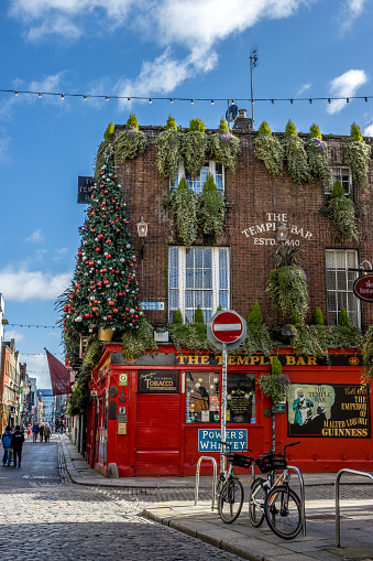 Dublin, Ireland – March 21, 2021: Dublin, Ireland, a shot of a red temple bar in the corner of the street with a Christmas tree