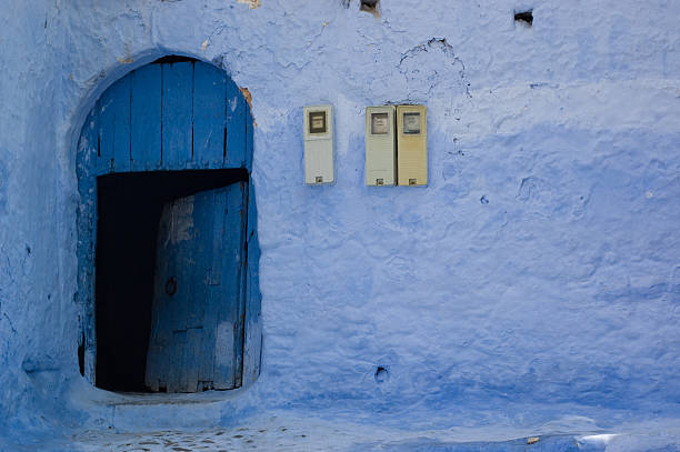 Pequeno porta de madeira em uma parede azul, com eletricidade metros - foto de acervo