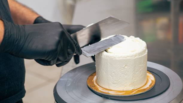 istock baker chef decorating cup cakes with cream and salty caramel using black gloves 1442903569