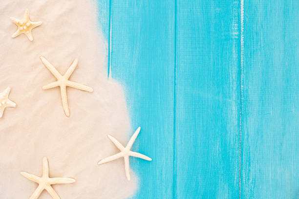 Summer-themed composition with sand and starfish on a blue surface