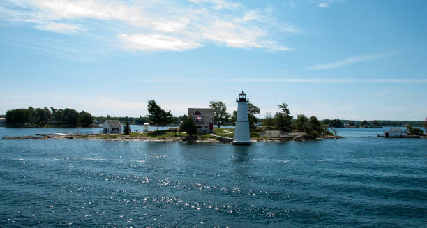 istock Lighthouse on peninsula on wavy water near dense forests under clear sky at sunlight 1442907803
