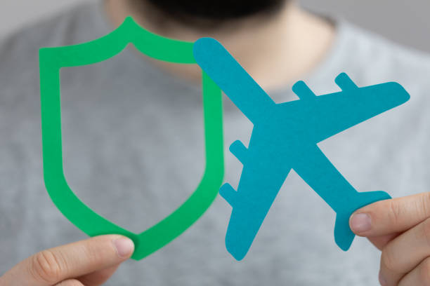 istock Male's hands holding a paper airplane and a shield - safe flight concept 1442908675