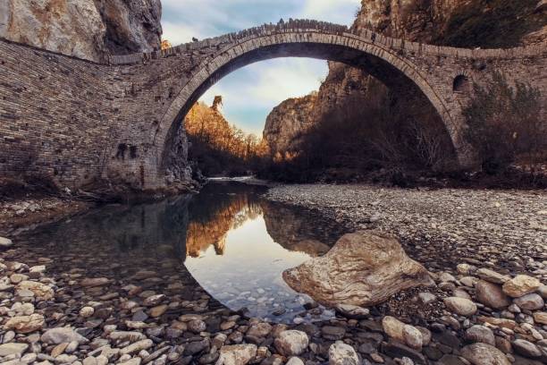 Low angle shot of a beautiful stone arch bridge in Zagori, Greece with a pile of water underneath it A low angle shot of a beautiful stone arch bridge in Zagori, Greece with a pile of water underneath it zagori stock pictures, royalty-free photos & images