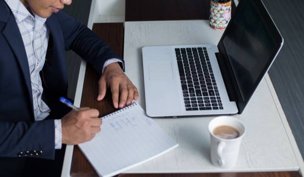 chłopak z azji południowo-wschodniej z malezji pracujący na laptopie i notatniku ubrany profesjonalnie - southeast asian ethnicity men laptop image type zdjęcia i obrazy z banku zdjęć